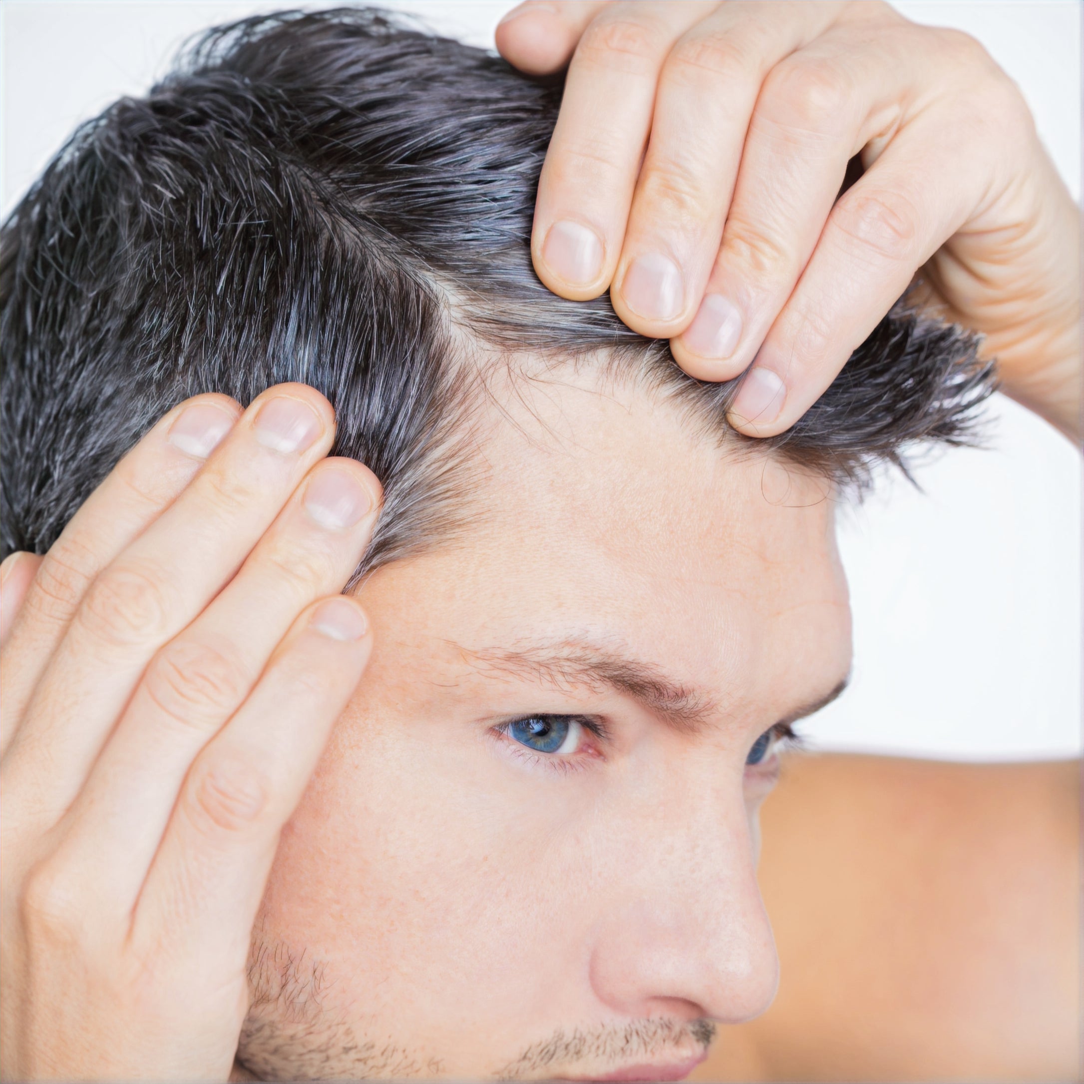 Junger Mann kontrolliert eigenen Haaransatz – erste Anzeichen von frühzeitigem Haarausfall