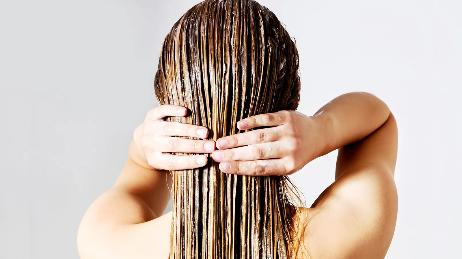 Nasses, frisch gepflegtes Haar wird mit beiden Händen gehalten – Sinnbild für intensive Haarpflege und Regeneration