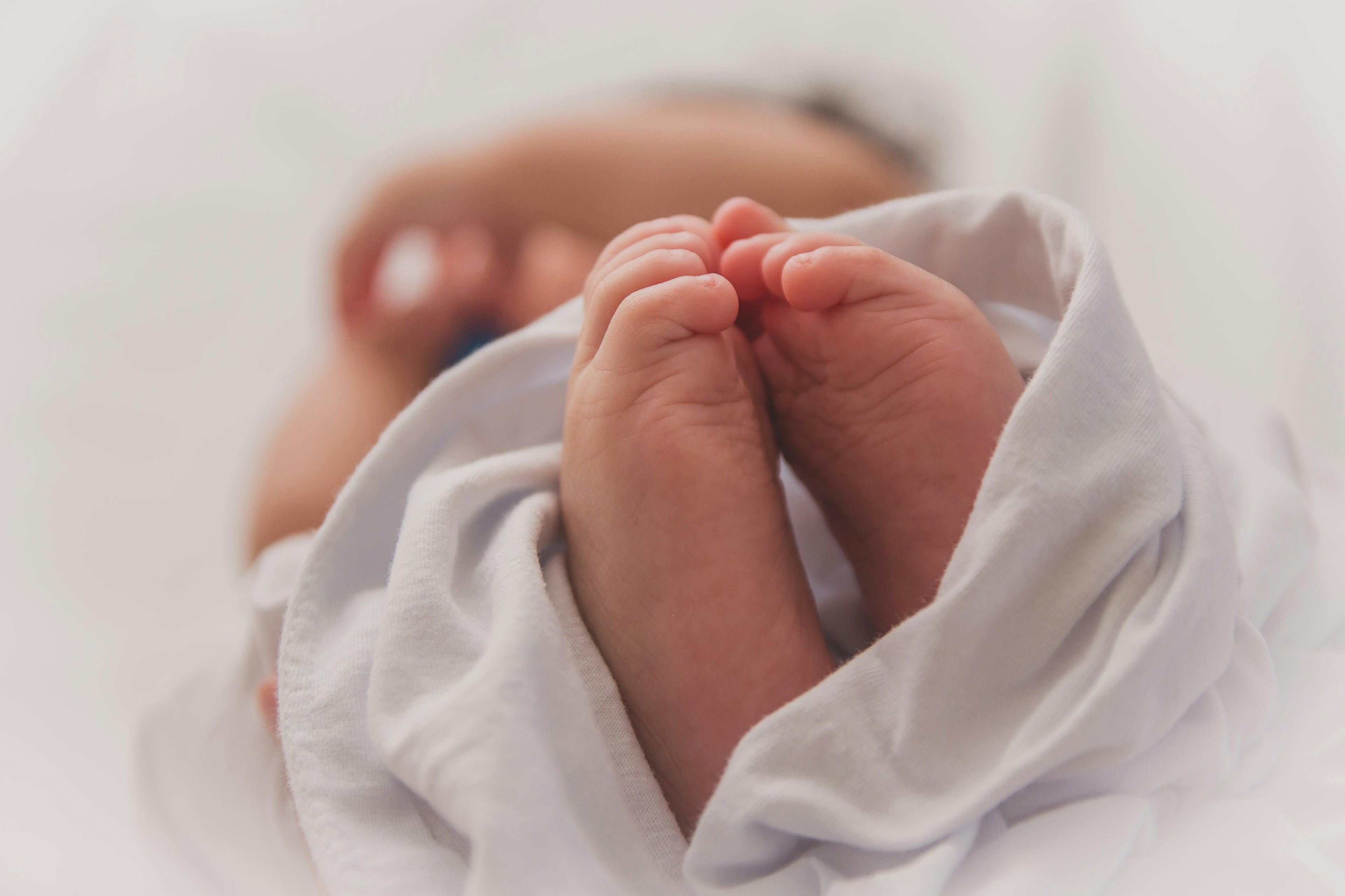 Babyfüsse in Decke gewickelt – Symbolbild für die Zeit nach der Geburt
